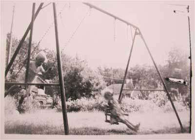 Cheryl Unruh on a backyard swingset, 1963.