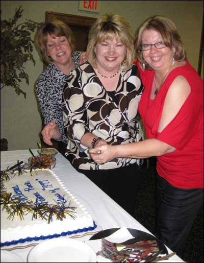 The class cake is cut by Marilyn Stimatze Murphy, Darla Dirks Clarke, and Jeanette Ater Corbett. (Cheryl Unruh took these photos.)