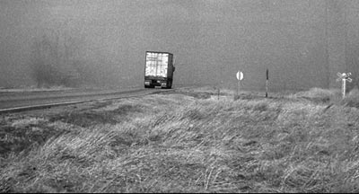 During a dust storm in the late 1970s, an 18-wheeler rides the wind on U.S. 56 a mile northeast of Pawnee Rock near the waterhole with the Texaco sign. Photo copyright 2008 by Leon Unruh.