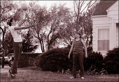 Greg Davidson hits a volleyball as William Buller watches in the front yard of Earl and Maxlyn Schmidt's home north of Pawnee Rock. Photo copyright 1974 by Leon Unruh.