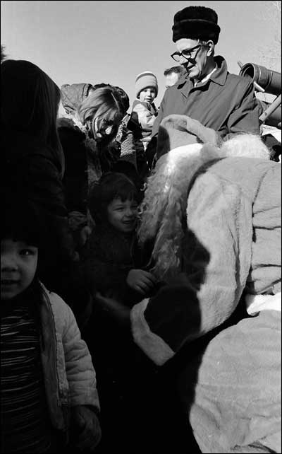 Santa gives a sack of candy and nuts and gets a smile in return. Photo copyright 2008 by Leon Unruh.